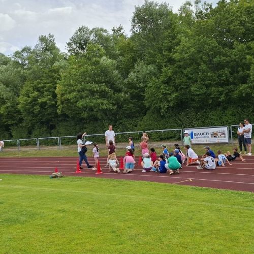 Kinder sitzen auf der Tartanbahn